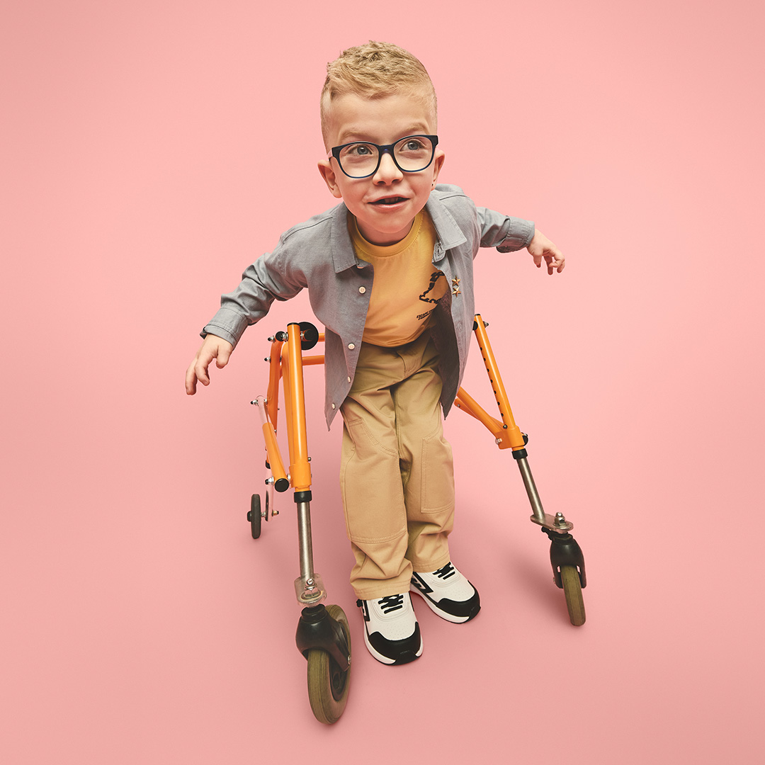 A boy using a walking frame leans forward and looks to the left.